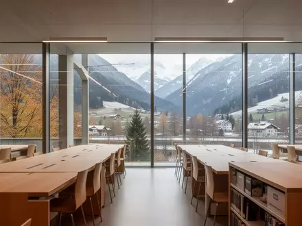 Moderner, minimalistischer Lernbereich in einer Schweizer Universitätsbibliothek mit Blick auf eine herbstliche Alpenlandschaft. - Foto: über boerse-global.de