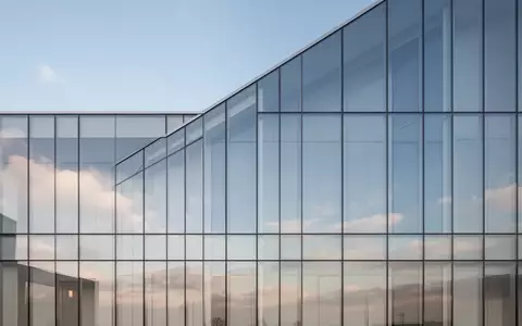 Moderne Glasfassade eines Bürogebäudes bei Tageslicht mit Spiegelung des Himmels - Foto: über boerse-global.de