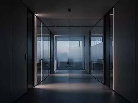 Ein leerer, modern gestalteter Büroflur mit klaren architektonischen Linien und gedimmtem Licht. - Foto: über boerse-global.de
