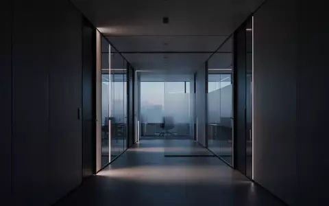 Ein leerer, modern gestalteter Büroflur mit klaren architektonischen Linien und gedimmtem Licht. - Foto: über boerse-global.de
