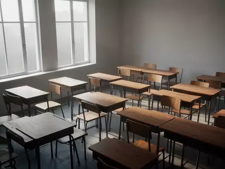 Ein leerer, sonnendurchfluteter Klassenraum mit schlichten Holztischen und Stühlen in einer ruhigen Lernumgebung. - Foto: über boerse-global.de