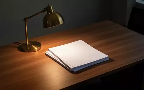 Ein leerer, aufgeräumter Schreibtisch mit einer Schreibtischlampe und einem Stapel unbeschriebener weißer Blätter. - Foto: über boerse-global.de