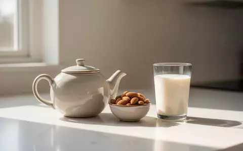 Eine Teekanne, eine Schale mit Mandeln und ein Glas Milch auf einer hellen Küchentheke im natürlichen Sonnenlicht. - Foto: über boerse-global.de