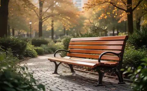 Eine leere Parkbank auf einem ruhigen Weg in einem grünen Park, umgeben von Bäumen und Sträuchern. - Foto: über boerse-global.de