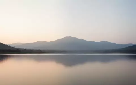 Eine weite, ruhige Berglandschaft bei Sonnenaufgang mit sanftem, diffusem Licht, die eine Atmosphäre der Stille vermittelt. - Foto: über boerse-global.de