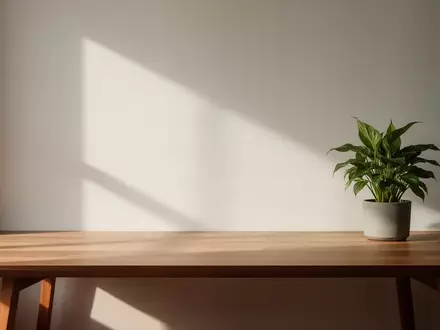 Ein minimalistischer Arbeitsplatz mit einem Holztisch und einer Pflanze bei natürlichem Licht. - Foto: über boerse-global.de