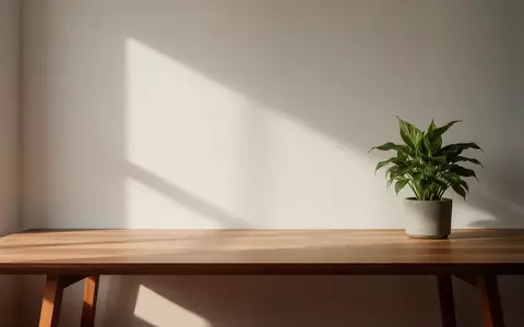 Ein minimalistischer Arbeitsplatz mit einem Holztisch und einer Pflanze bei natürlichem Licht. - Foto: über boerse-global.de