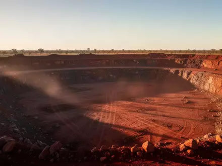 Weite, staubige Tagebaulandschaft im australischen Outback bei Sonnenaufgang mit tiefen Gesteinsschichten und langen Schatten. - Foto: über boerse-global.de