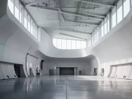 Minimalistische, architektonische Windkanal-Testanlage mit geschwungenen Betonwänden und diffusem Tageslicht. - Foto: über boerse-global.de