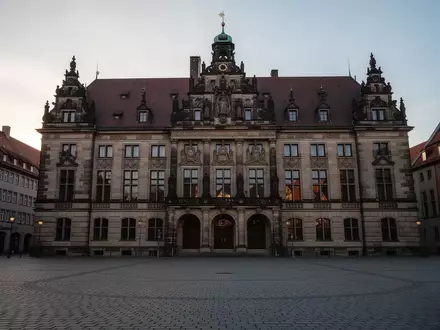 Fassade eines historischen deutschen Rathauses in der Abenddämmerung mit leerem Kopfsteinpflasterplatz im Vordergrund. - Foto: über boerse-global.de