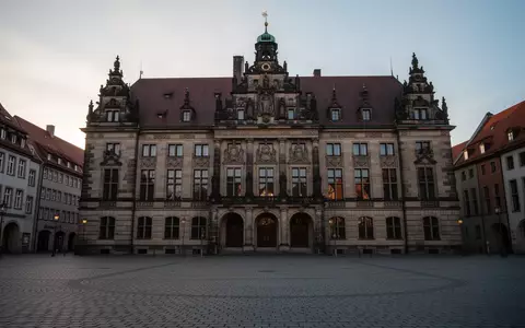 Fassade eines historischen deutschen Rathauses in der Abenddämmerung mit leerem Kopfsteinpflasterplatz im Vordergrund. - Foto: über boerse-global.de