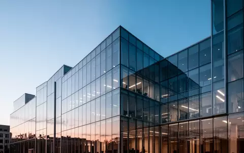 Moderne, minimalistische Glasarchitektur eines Bürogebäudes in der Dämmerung, die Stabilität und strukturellen Wandel symbolisiert. - Foto: über boerse-global.de