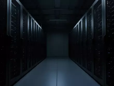 Ein dunkler, leerer Serverraum mit Reihen von Server-Racks in kühlem, blauem Licht. - Foto: über boerse-global.de