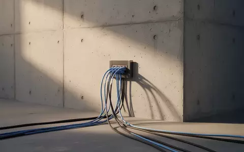 Ein minimalistisches Glasfaser-Anschlusskabel an einer Betonwand in sanftem, natürlichem Licht. - Foto: über boerse-global.de