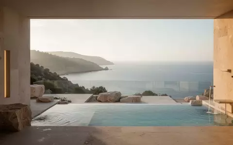 Eine sonnendurchflutete Hotelterrasse mit Blick auf eine ruhige Küstenlandschaft, minimalistische Architektur und natürliche Steinelemente. - Foto: über boerse-global.de