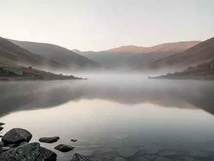 Ein ruhiger, nebliger Bergsee bei Tagesanbruch als Symbol für Stille und Entschleunigung. - Foto: über boerse-global.de