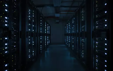 Dunkler Serverraum mit blau leuchtenden Statusanzeigen an Hardware-Racks. - Foto: über boerse-global.de