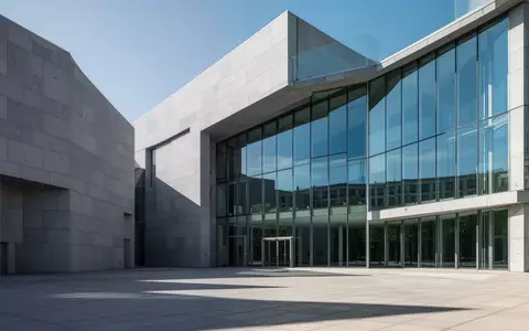 Ein minimalistisches, modernes Regierungsgebäude mit einer Fassade aus grauem Stein und großen Glasflächen bei Tageslicht. - Foto: über boerse-global.de