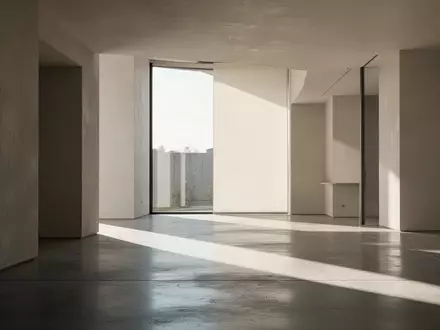 Ein minimalistischer, moderner Innenraum mit klaren geometrischen Linien und natürlichem Lichteinfall auf einem Betonboden. - Foto: über boerse-global.de