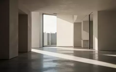 Ein minimalistischer, moderner Innenraum mit klaren geometrischen Linien und natürlichem Lichteinfall auf einem Betonboden. - Foto: über boerse-global.de