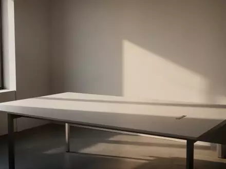 Ein minimalistischer, leerer Schreibtisch in einem hellen, sonnendurchfluteten Raum mit sanften Schatten. - Foto: über boerse-global.de