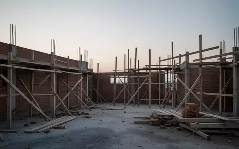 Eine ruhige Baustelle mit unfertigem Mauerwerk und Gerüsten in der Dämmerung, die die wirtschaftliche Flaute im Handwerk symbolisiert. - Foto: über boerse-global.de