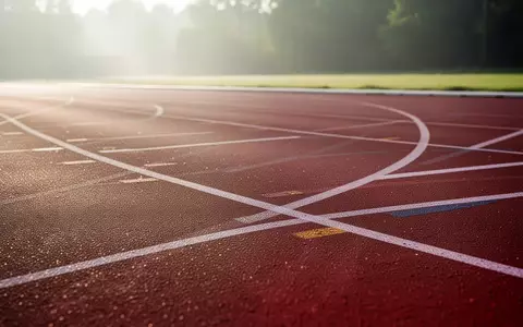 Eine leere, von der Morgensonne beleuchtete Laufbahn auf einem Sportplatz. - Foto: über boerse-global.de