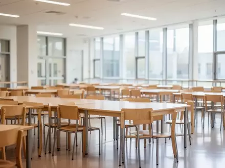 Leerer, heller Speiseraum in einer Schule mit Holztischen und Stühlen bei Tageslicht. - Foto: über boerse-global.de