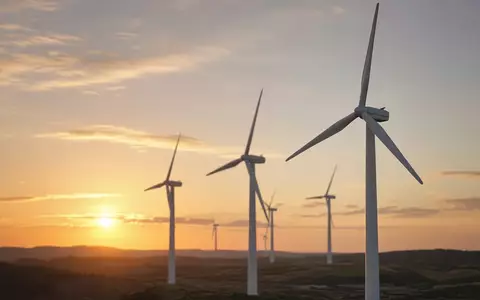 Moderne Windkraftanlagen bei Sonnenuntergang in einer weitläufigen Landschaft. - Foto: über boerse-global.de