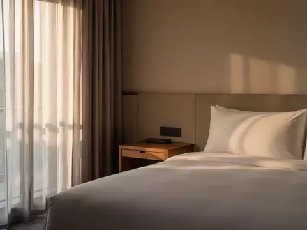 Ein minimalistisch eingerichtetes, ruhiges Hotelzimmer mit sanftem Tageslicht als Symbol für einen sicheren Rückzugsort. - Foto: über boerse-global.de