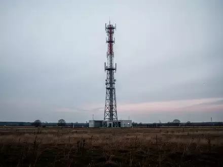 Ein einsamer Sendemast für Rundfunkübertragungen in einer weiten, offenen Landschaft unter einem wolkenverhangenen Himmel. - Foto: über boerse-global.de