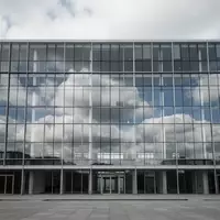 Ein modernes, leeres Bürogebäude mit Glasfassade spiegelt den bewölkten Himmel wider. - Foto: über boerse-global.de