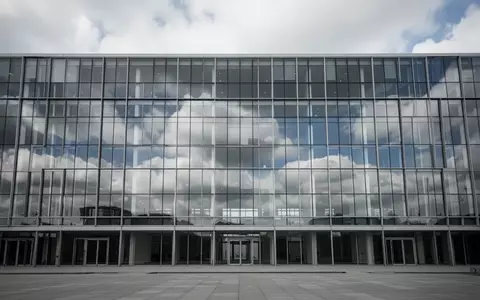 Ein modernes, leeres Bürogebäude mit Glasfassade spiegelt den bewölkten Himmel wider. - Foto: über boerse-global.de