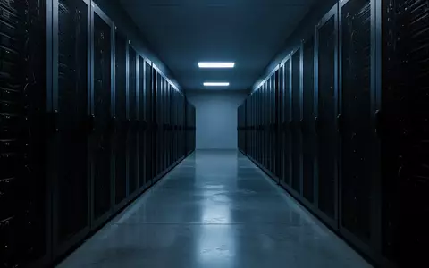 Ein minimalistisch beleuchteter Serverraum mit dunklen Regalsystemen und kühlem blauem Licht auf einem Betonboden. - Foto: über boerse-global.de