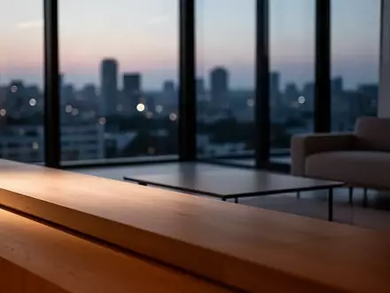 Ein minimalistisch eingerichtetes, modernes Wohnzimmer während der Dämmerung mit weichem Licht und Blick auf eine Stadtkulisse. - Foto: über boerse-global.de