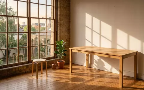 Ein minimalistischer, sonnendurchfluteter Arbeitsbereich mit einem leeren Holztisch und weichem Tageslicht. - Foto: über boerse-global.de
