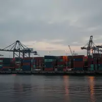 Blick auf einen industriellen Containerhafen mit Kränen und gestapelten Frachtcontainern bei Dämmerung. - Foto: über boerse-global.de