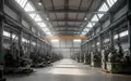 Innenansicht einer modernen, weitläufigen Industriehalle mit großen Maschinen und Stahlträgern bei natürlichem Licht. - Foto: über boerse-global.de