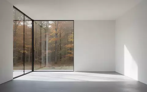 Minimalistischer, heller Innenraum mit klaren architektonischen Linien und Blick auf einen herbstlichen Wald - Foto: über boerse-global.de