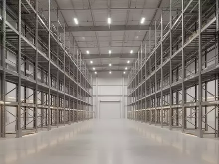 Ein weites, modernes Logistiklager mit hohen, leeren Metallregalen und einem polierten Betonboden in einer Industriehalle. - Foto: über boerse-global.de