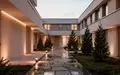 Ein ruhiger Innenhof einer Pflegeeinrichtung in der Abenddämmerung mit minimalistischer Architektur und einem Garten. - Foto: über boerse-global.de
