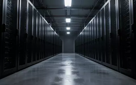 Eine weitläufige, düstere Serverhalle mit endlosen Reihen dunkler Metallschränke in einer sterilen, technologischen Umgebung. - Foto: über boerse-global.de