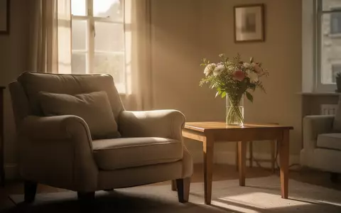 Ein ruhiges, sonnendurchflutetes Wohnzimmer mit einem bequemen Sessel und einer Vase mit frischen Blumen. - Foto: über boerse-global.de