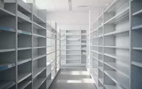 Ein minimalistisch gestalteter, heller Verkaufsraum einer Apotheke mit leeren Regalen in ruhiger, natürlicher Beleuchtung. - Foto: über boerse-global.de