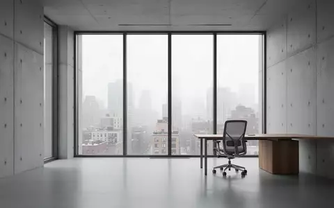 Ein minimalistisches, modernes Büro mit großen Fenstern und Blick auf eine städtische Skyline bei natürlichem Tageslicht. - Foto: über boerse-global.de