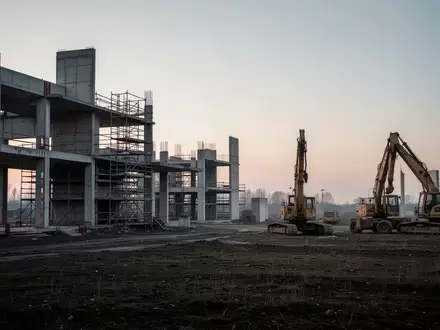 Eine verlassene Baustelle mit unfertigen Betongebäuden und Baugerüsten in der Dämmerung. - Foto: über boerse-global.de