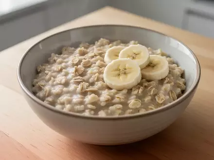 Eine Nahaufnahme einer Schüssel mit Haferbrei und Bananenscheiben auf einem Holztisch, die eine gesunde Ernährung nach einer Krankheit symbolisiert. - Foto: über boerse-global.de