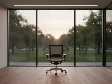 Ein leerer, ergonomischer Bürostuhl in einem minimalistischen Raum mit Blick auf einen grünen Park. - Foto: über boerse-global.de