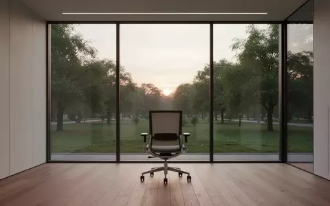 Ein leerer, ergonomischer Bürostuhl in einem minimalistischen Raum mit Blick auf einen grünen Park. - Foto: über boerse-global.de