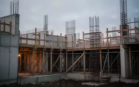 Halb fertiggestellter Rohbau eines Wohngebäudes bei Dämmerung mit Betonwänden und Gerüst. - Foto: über boerse-global.de